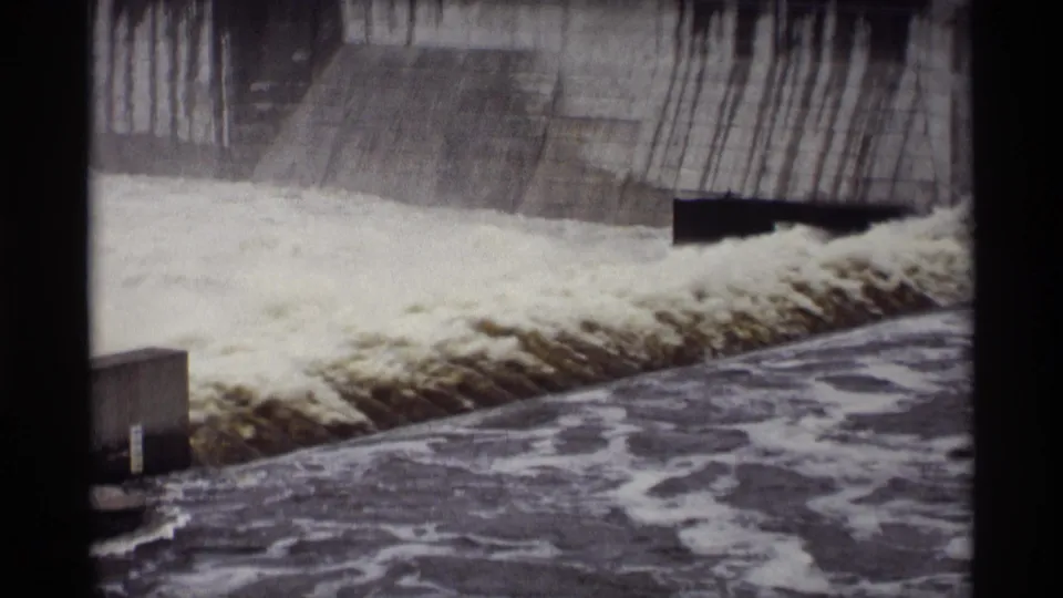 Vintage 8mm frame showing sustained water flow over the concrete spillway at the documented 1969 Minnesota site.