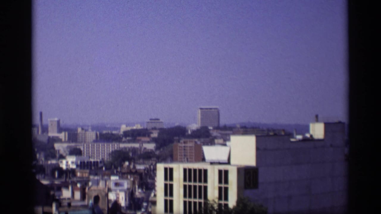 Similar elevated skyline view with taller buildings and dark film borders.