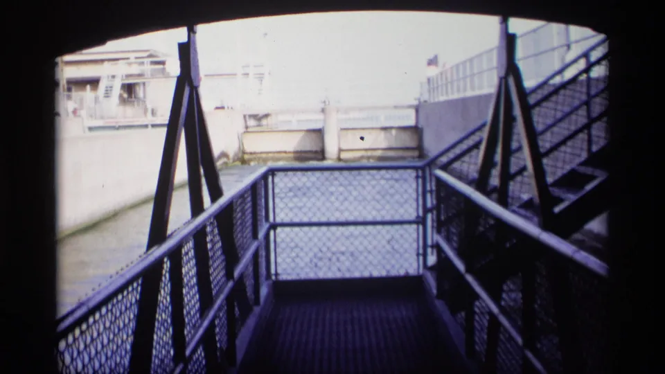 1969 Wisconsin 8mm frame with a metal walkway, railings, stairs, and concrete canal infrastructure in bright exposure.