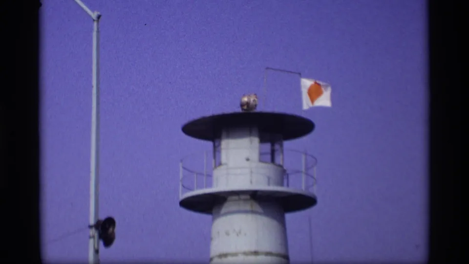 1969 Wisconsin 8mm frame showing a white maritime tower with circular platforms, a light fixture, and a flag against a purple-blue sky.
