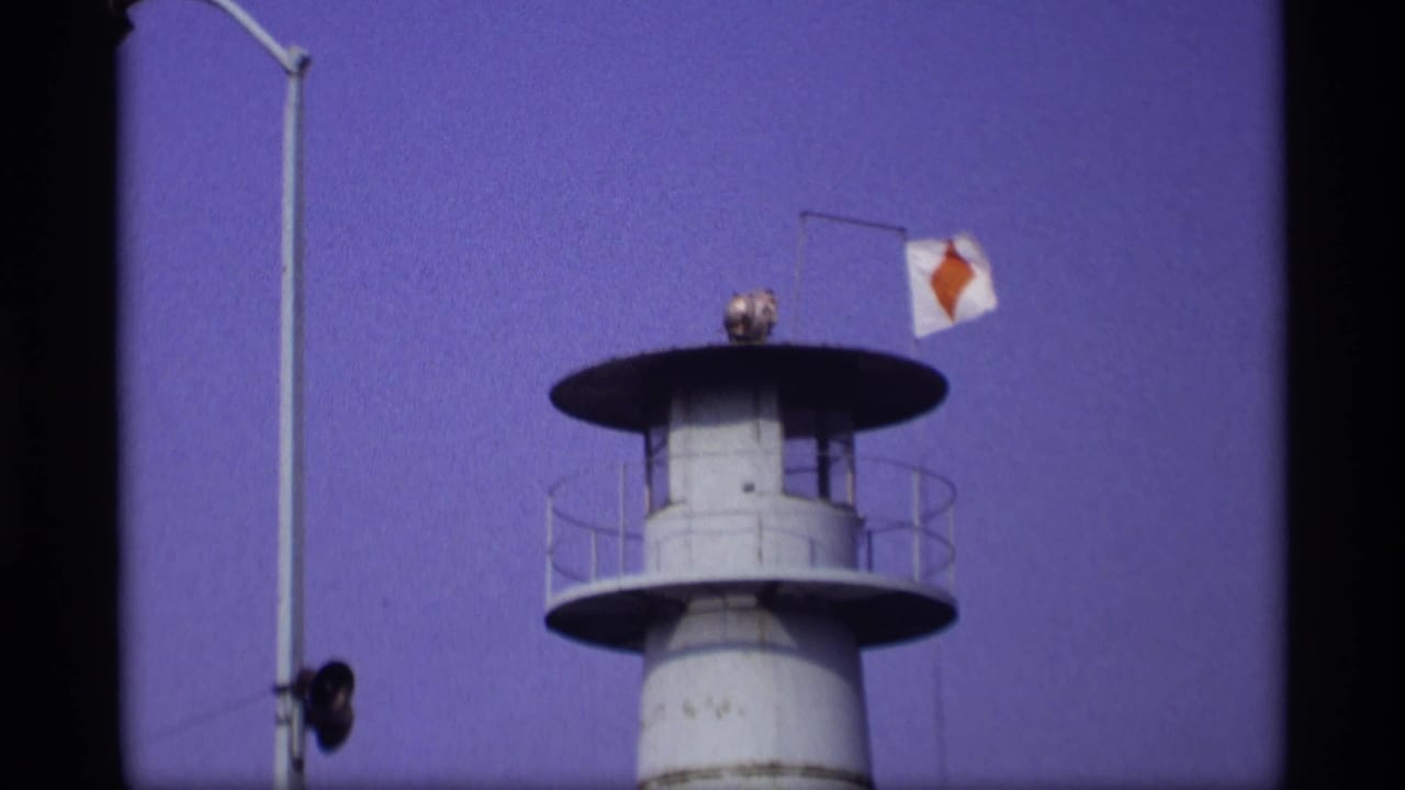 White watchtower with railings and a small flag against a blue sky.