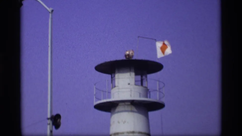 1969 Wisconsin 8mm frame showing a white canal-side watchtower or control structure with railings and a small diamond-marked flag.