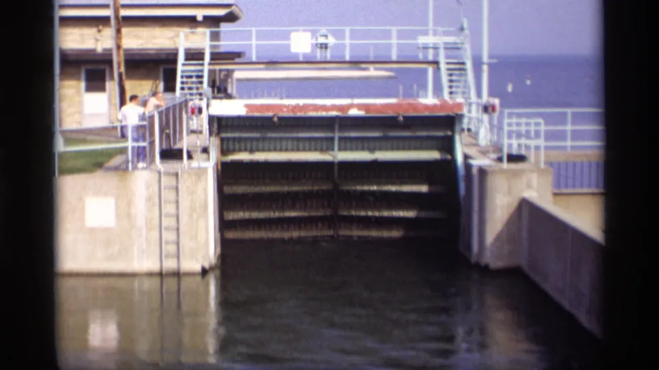 Final 1969 Wisconsin frame showing the raised bridge gate, exposed mechanism, water below, and observers at the rail.