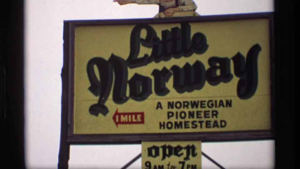 1969 Wisconsin 8mm frame of a Little Norway sign advertising a Norwegian pioneer homestead one mile away, open 9 AM to 7 PM.