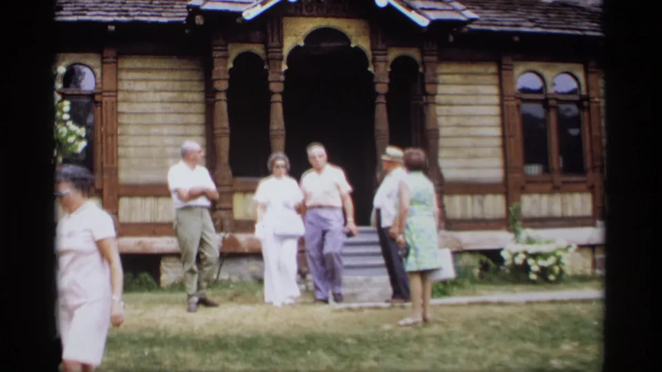 Tourists in summer clothes stand and talk near the entrance of a historic-looking wooden building in Wisconsin, 1969.