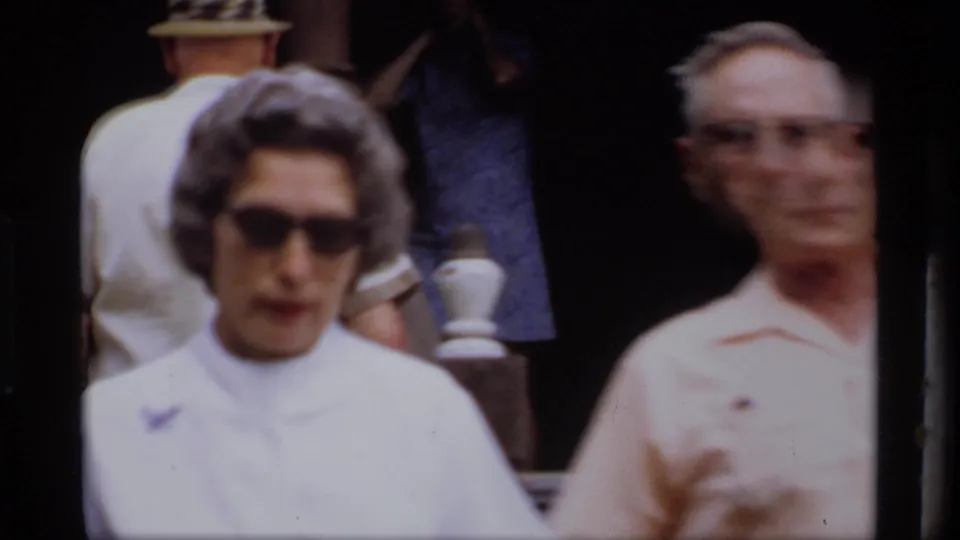 Close, softly focused 1969 Wisconsin home-movie view of a woman in sunglasses and a man near the older house porch.
