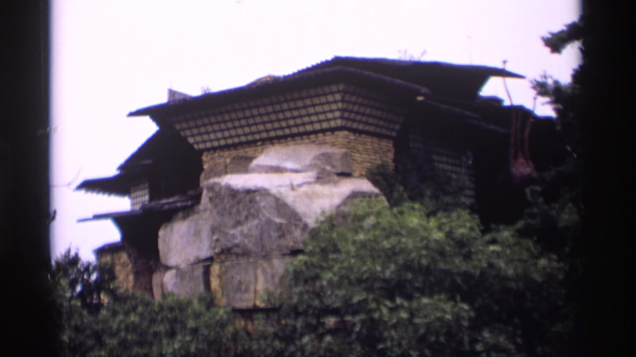 Japanese-style structure built among large rocks and trees.