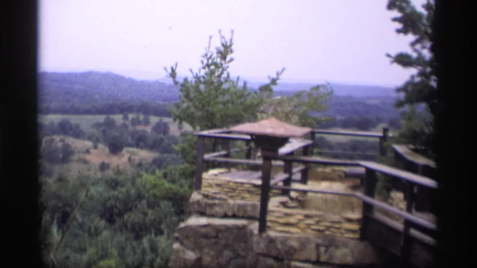 1969 Wisconsin home-movie view of a stone overlook platform and wooden railing looking across trees and rolling hills.