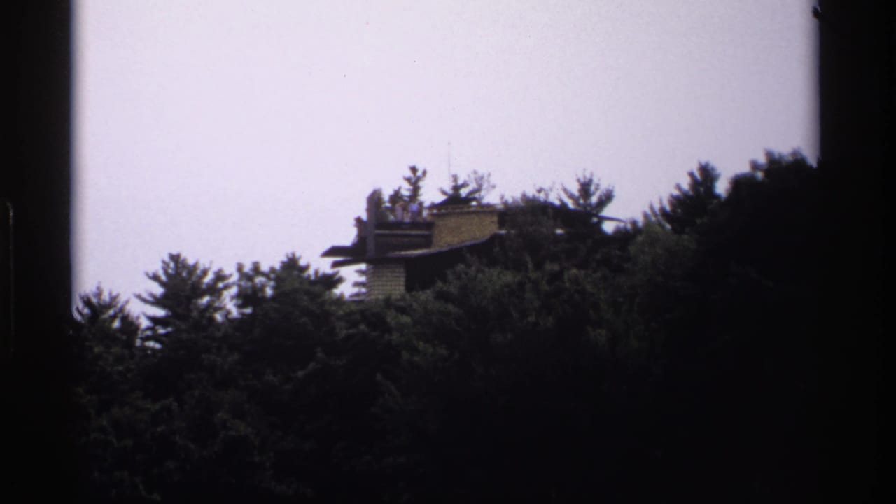 Similar distant view of a structure above trees with dark film borders.