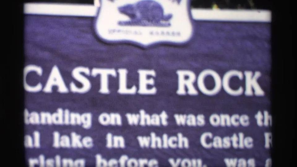 Close 1969 Wisconsin frame of a purple Castle Rock sign with white text and an animal emblem above it.