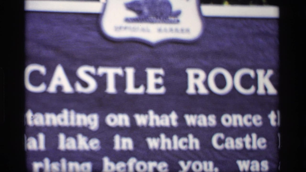 Close view of a Castle Rock sign with white lettering and dark film borders.