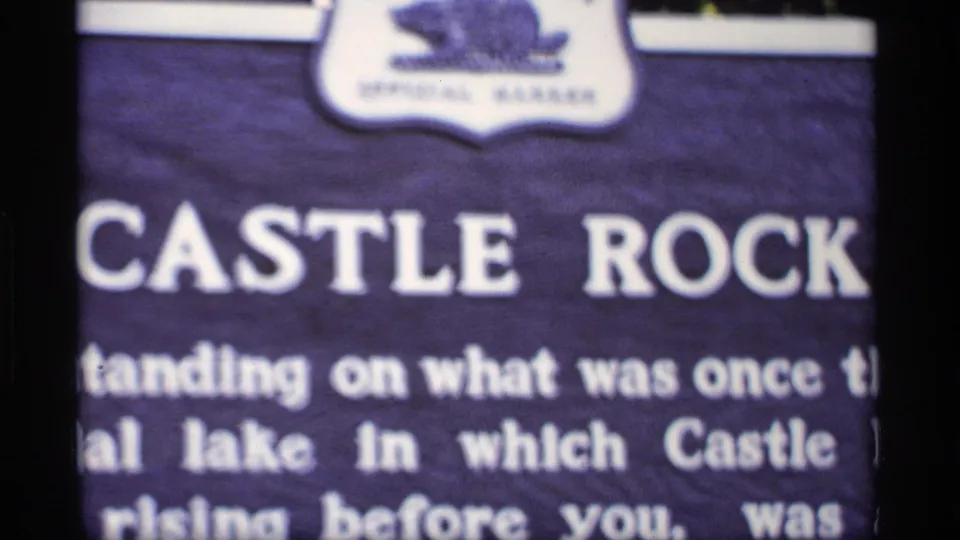 1969 Wisconsin 8mm frame showing a close, partly cropped Castle Rock sign with white lettering and soft focus.