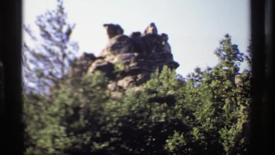 1969 Wisconsin 8mm view of the Castle Rock formation partly framed by dense trees and film gate edges.