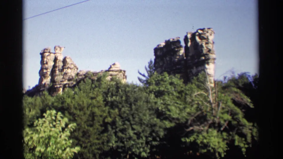 1969 Wisconsin frame showing sandstone outcrops, dense trees, and clear sky with home-movie film texture.