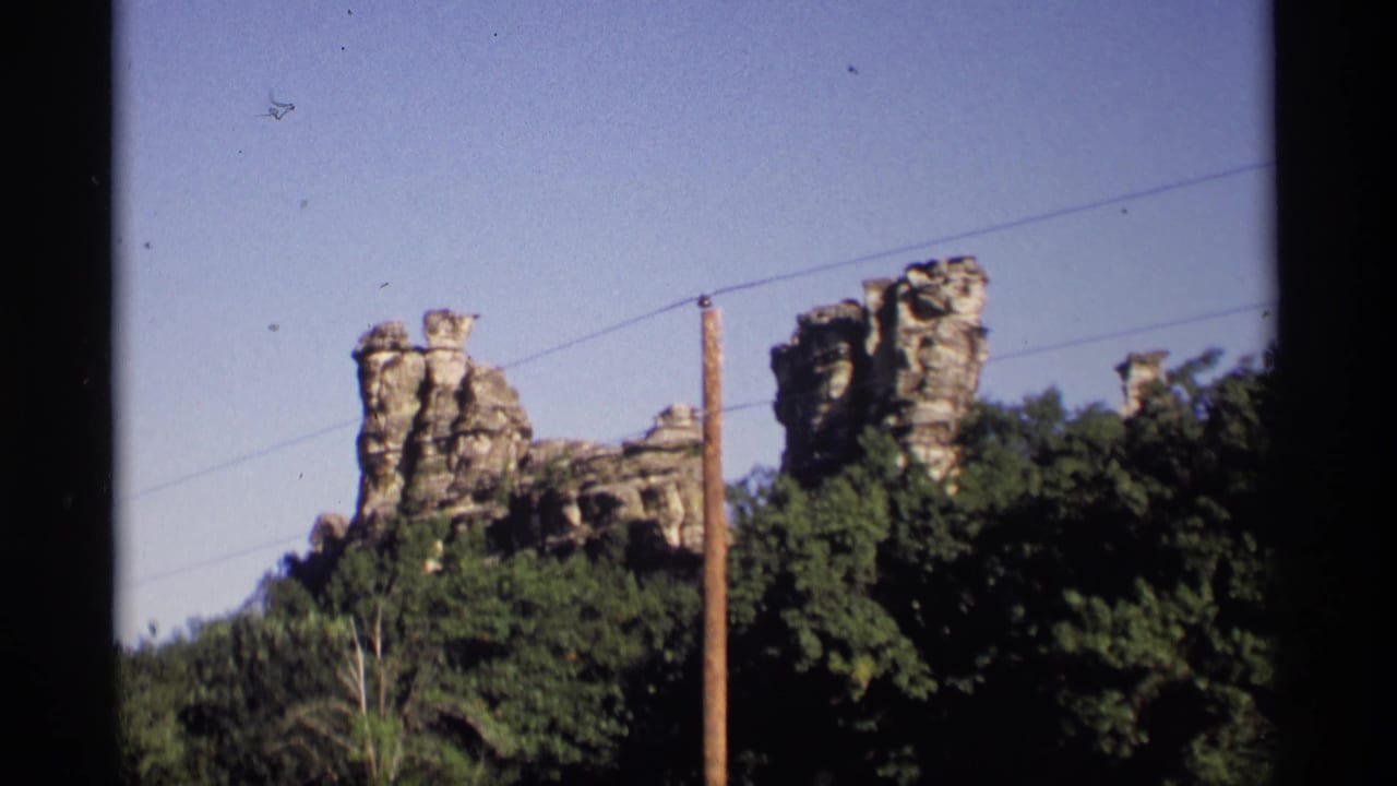 Rock spires, trees, a utility pole, and overhead wires beneath a clear sky.