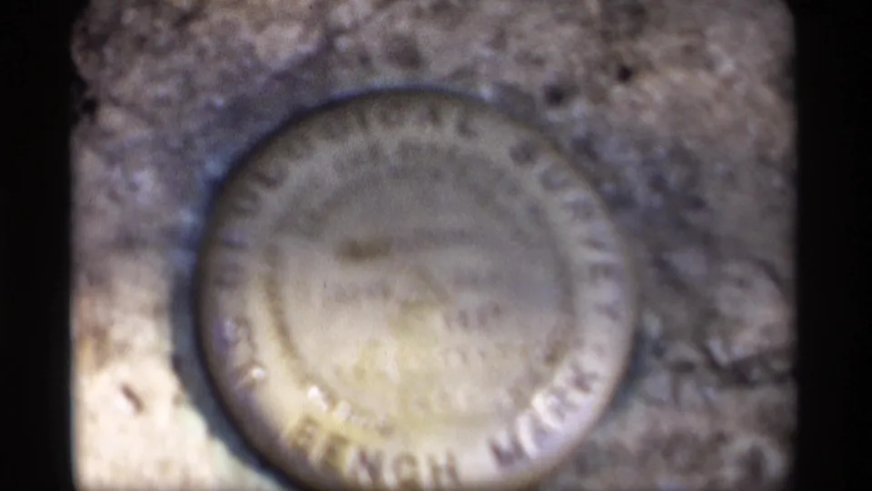 Zoomed 1969 Wisconsin frame with the circular bench mark filling much of the image on a rough stone surface.