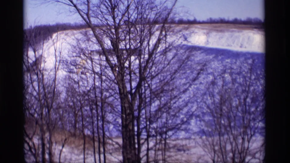The final frame holds on leafless trees and a snow-covered rural Wisconsin field, with a low winter hillside in the distance.