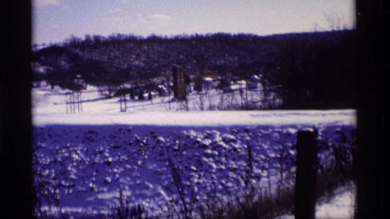 Snowy field and distant wooded hills seen from a winter overlook.