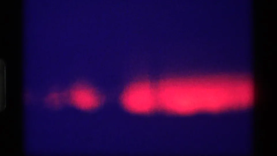1969 Wisconsin 8mm frame showing a red horizontal light smear across a dark blue night scene with visible film borders.