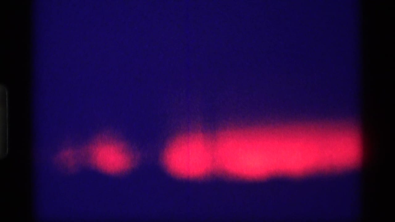 Bright red light band crosses a blue night scene with a dark vertical frame edge.