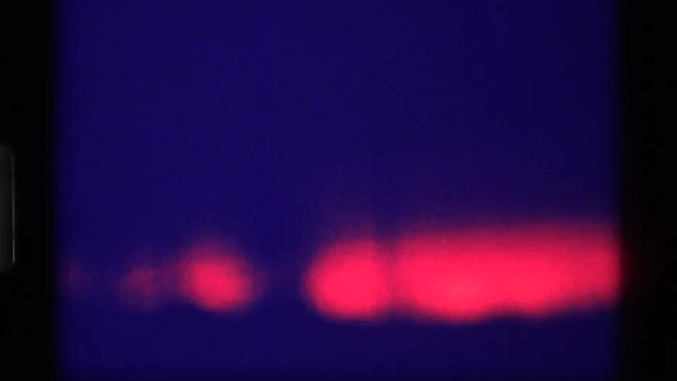 1969 Wisconsin 8mm frame showing a red glow low in the blue night scene, softened by grain and exposure.