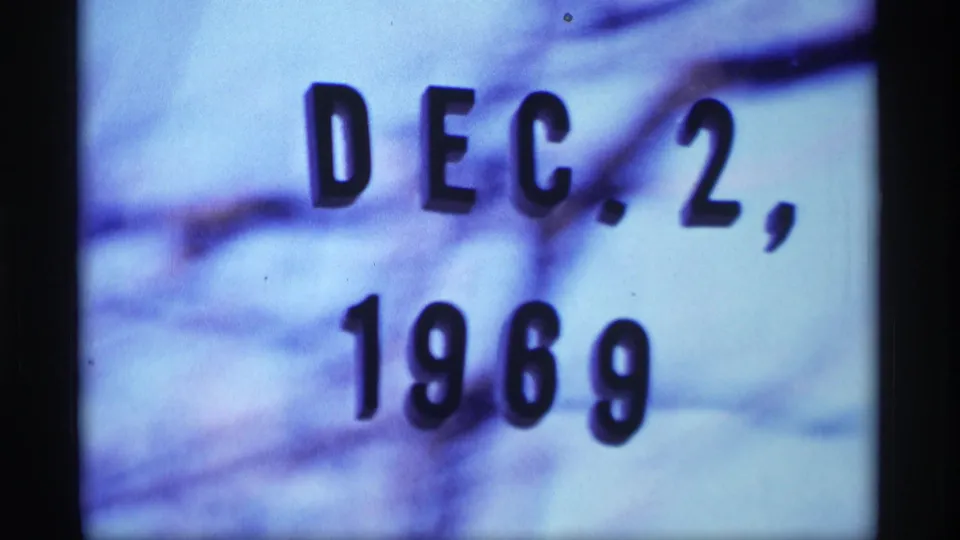 1969 Wisconsin 8mm frame showing a close-up date card reading Dec. 2, 1969 against a snowy blue-purple background.