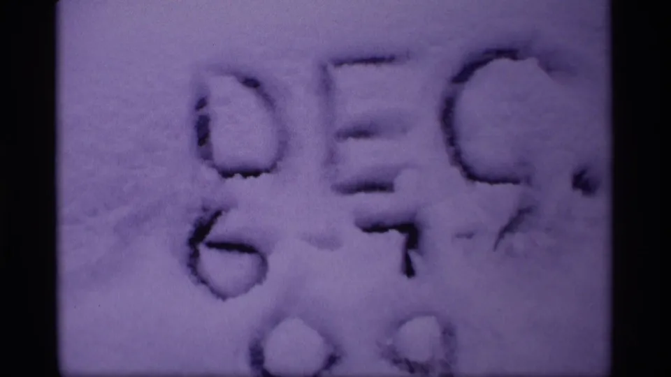 Purple-tinted 8mm frame showing faint Dec. lettering and numerals impressed or written in a snowy surface.