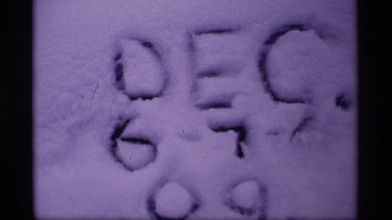 Handwritten letters and shapes pressed into snow with a purple film tint.