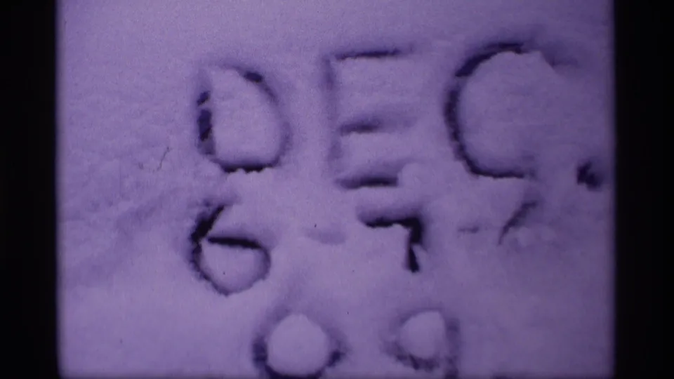 1969 Wisconsin 8mm frame showing handwritten markings in snow, softly focused with a purple archival film cast.
