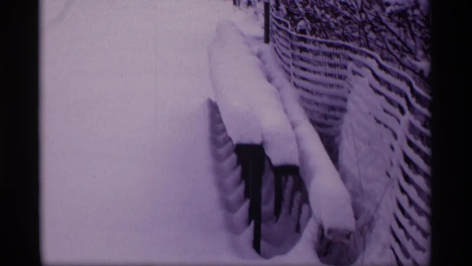 1969 Wisconsin 8mm frame showing snow piled on a fence, bench or railing, and a narrow yard path in winter.