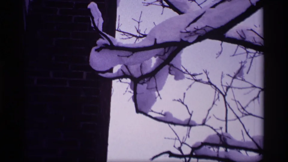 1969 Wisconsin 8mm frame showing snow-laden bare branches near a brick building under a pale winter sky.