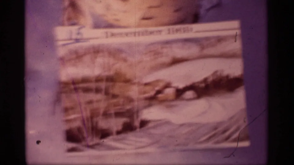 Blurred 8mm frame of a December 1969 winter postcard, with snow scene details softened by motion and focus.