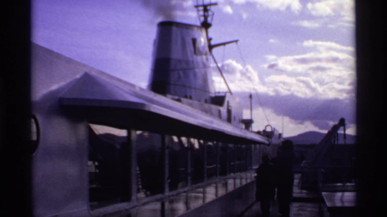 1974 Canadian 8mm view of a passenger ship deck with smoke rising from the funnel as people walk in silhouette.
