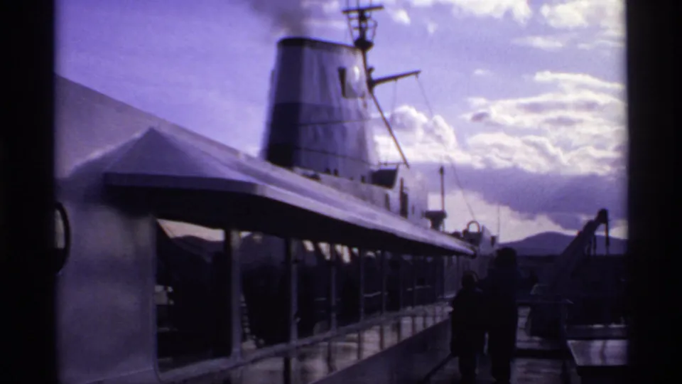 1974 Canadian 8mm view of a passenger ship deck with smoke rising from the funnel as people walk in silhouette.