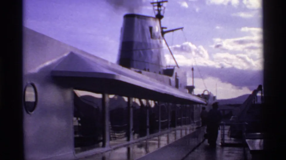 1974 Canadian home-movie view along the ship deck, with passengers in shadow and smoke drifting from the funnel.