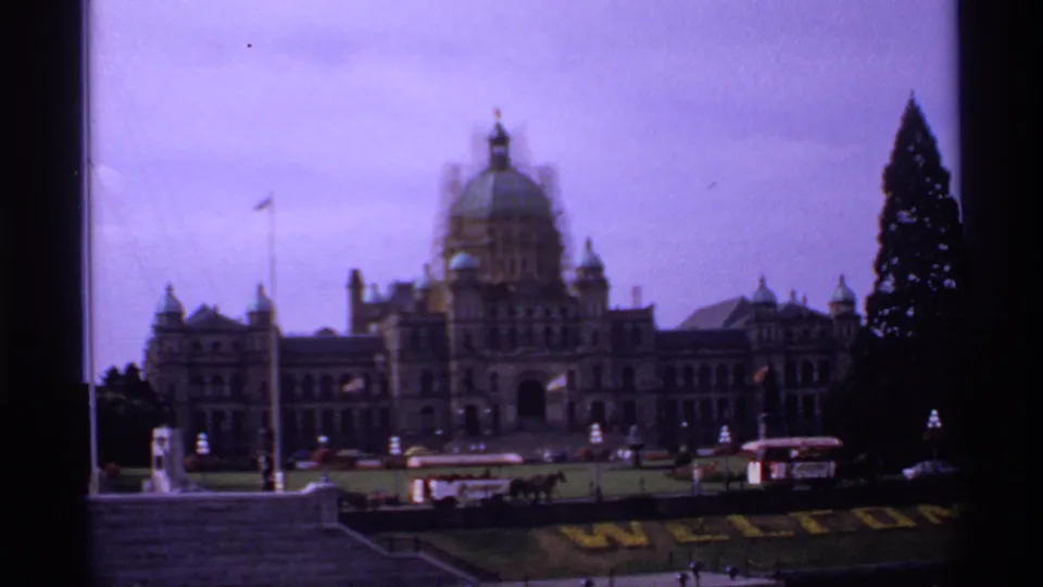 1974 Canada home-movie frame showing a domed civic-style building with lawns and trees, seen in soft focus before the ferry views.