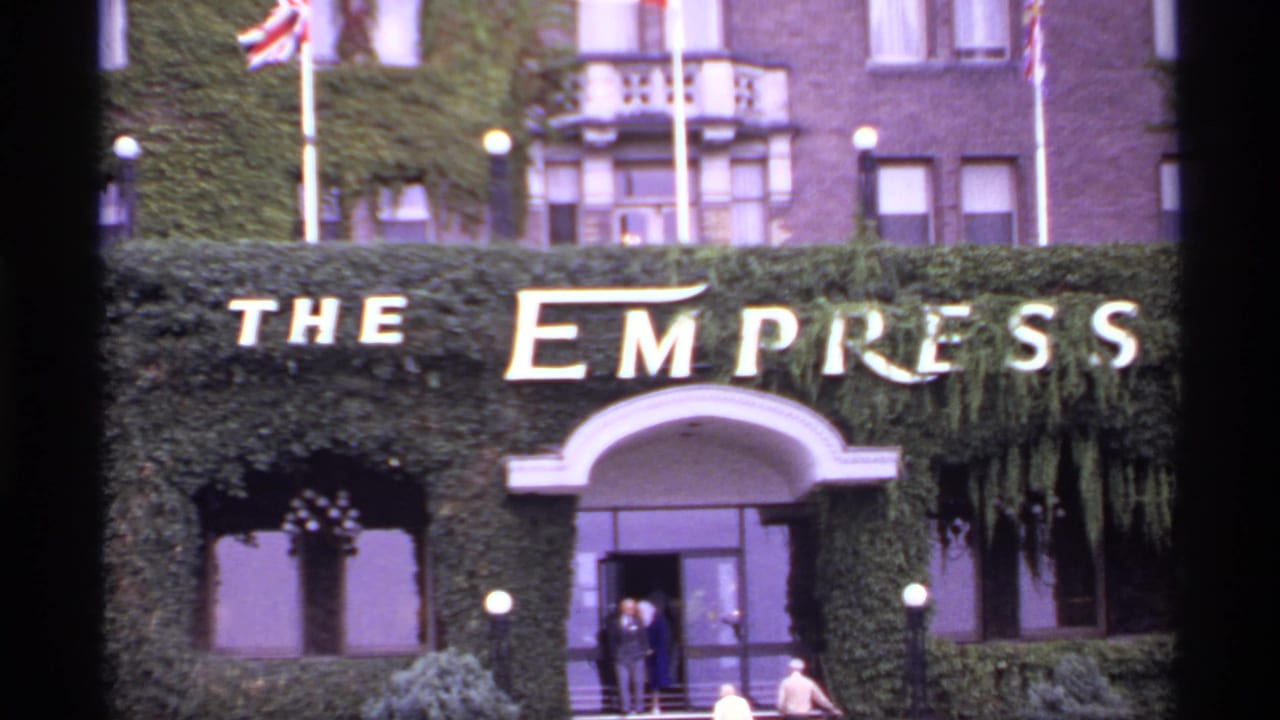 1974 Canada 8mm frame showing The Empress hotel sign above an ivy-covered entrance with flags and pedestrians nearby.