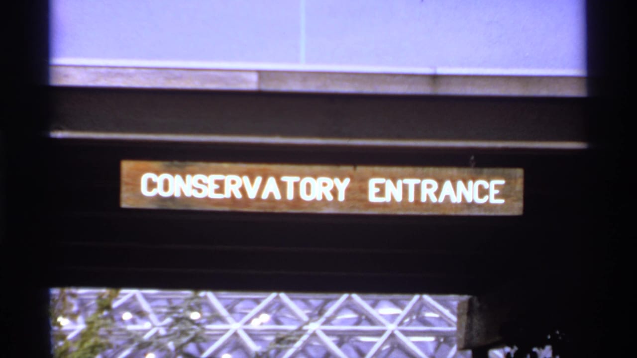 1974 Canadian 8mm frame showing a Conservatory Entrance sign over a dark exterior opening with part of a glass dome visible below.