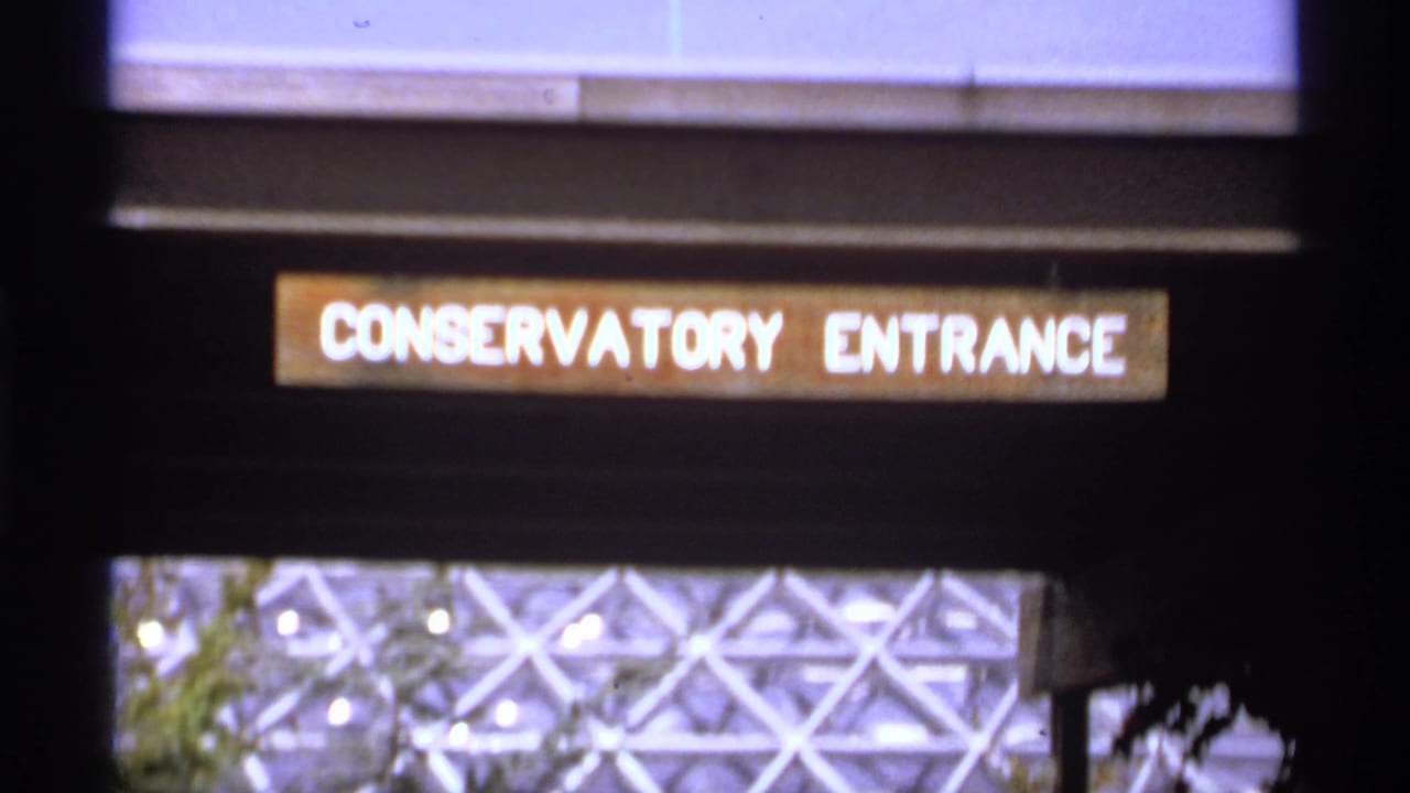 1974 Canadian 8mm frame with a Conservatory Entrance sign and the patterned glass-and-metal dome structure seen beneath it.
