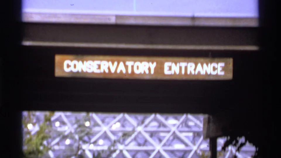 1974 Canadian 8mm frame with a Conservatory Entrance sign and the patterned glass-and-metal dome structure seen beneath it.