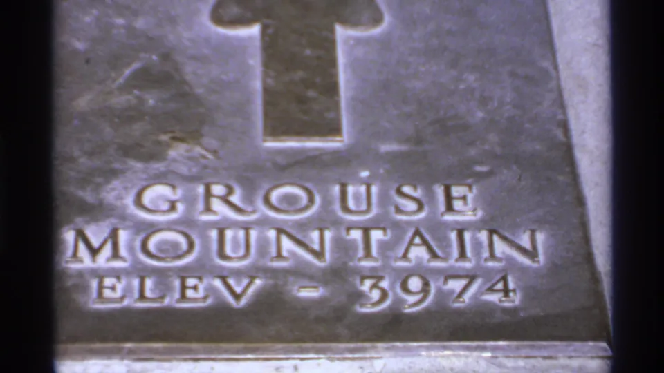 Close 1974 Canadian 8mm view of a metal Grouse Mountain elevation marker reading ELEV - 3974.