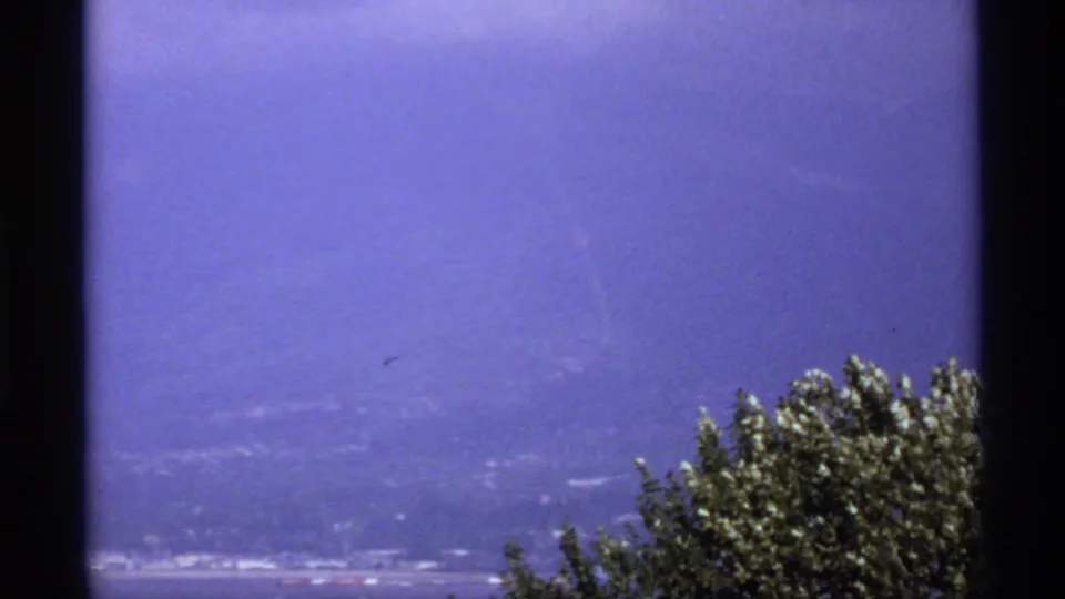1974 Canada 8mm summit view from Grouse Mountain, with hazy distant terrain and treetops under a saturated sky.