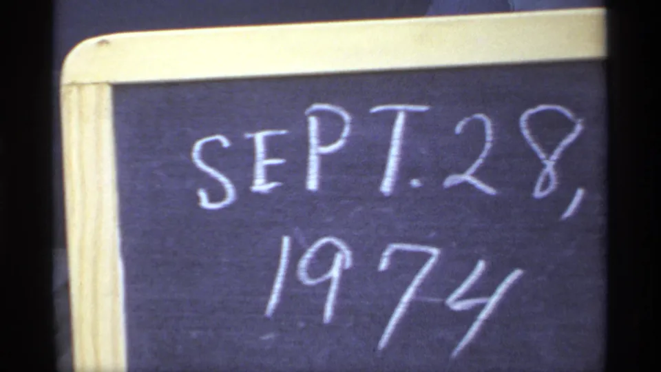 Close 8mm frame of a small chalkboard with SEPT. 28, 1974 written by hand, used as a home-movie date slate.