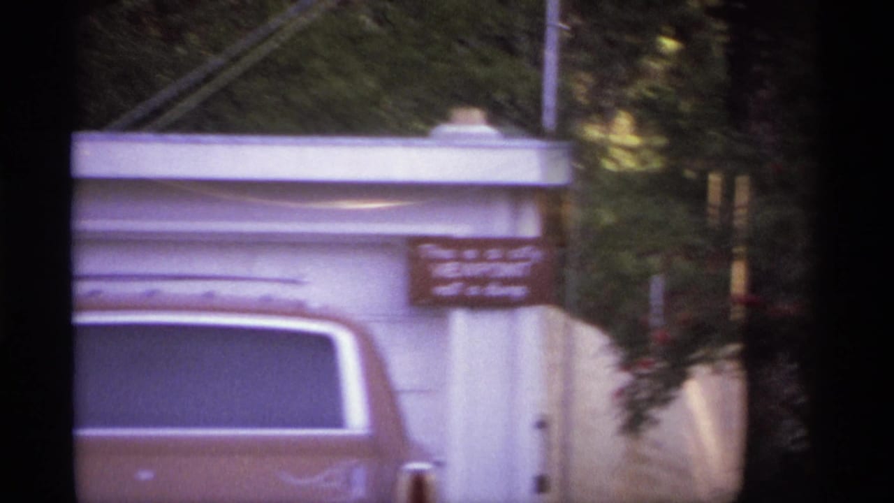 Soft view of the same station wagon and white structure with a warning sign at right.