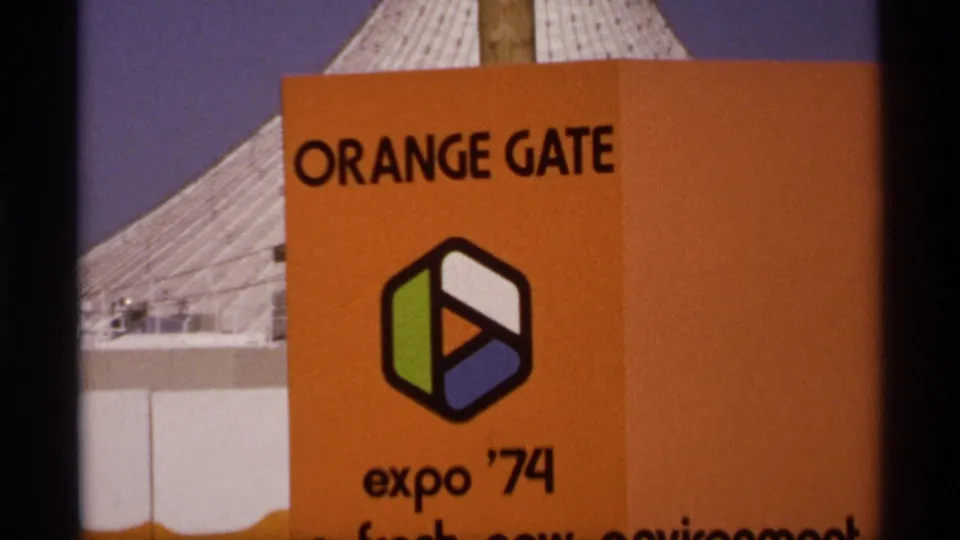 Close 1974 Spokane Expo frame showing the orange Orange Gate sign with Expo '74 logo and tent-like roof behind it.