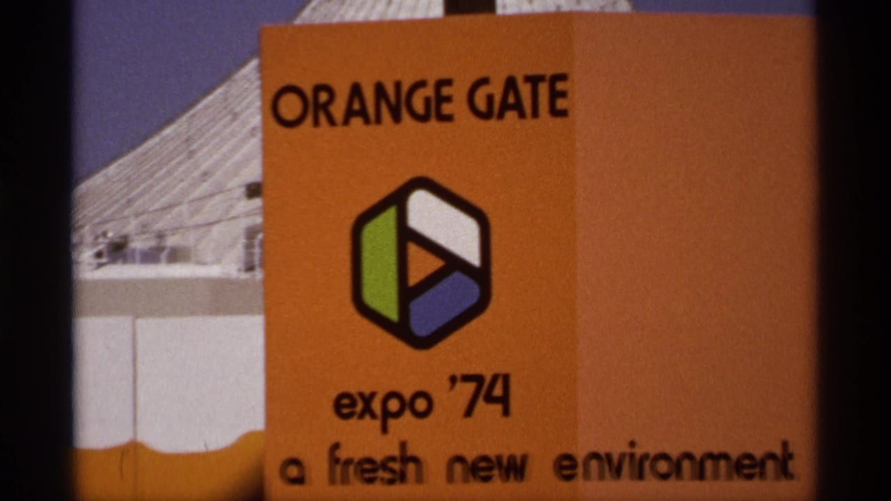 Spokane Expo '74 Orange Gate entrance sign with event logo, orange panel, and partial fair building in 1974 8mm footage.
