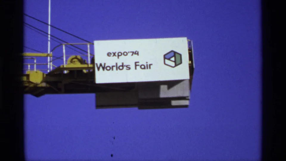 A closer visitor-shot view of the Expo '74 World's Fair sign and cube graphic on a raised structure in Spokane.