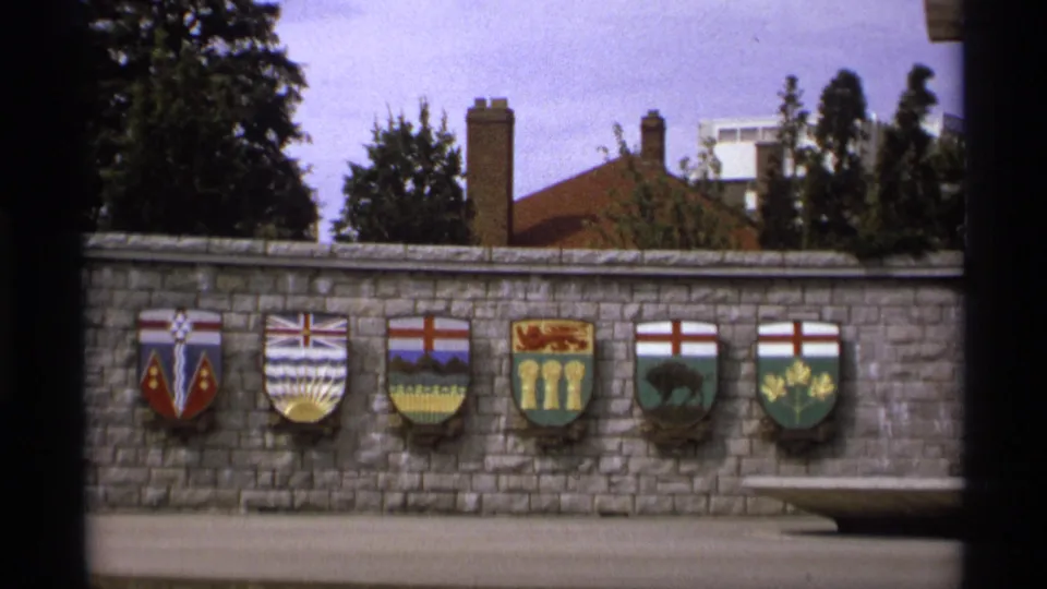 1974 Vancouver frame of a stone wall lined with colorful Canadian provincial or territorial shields.