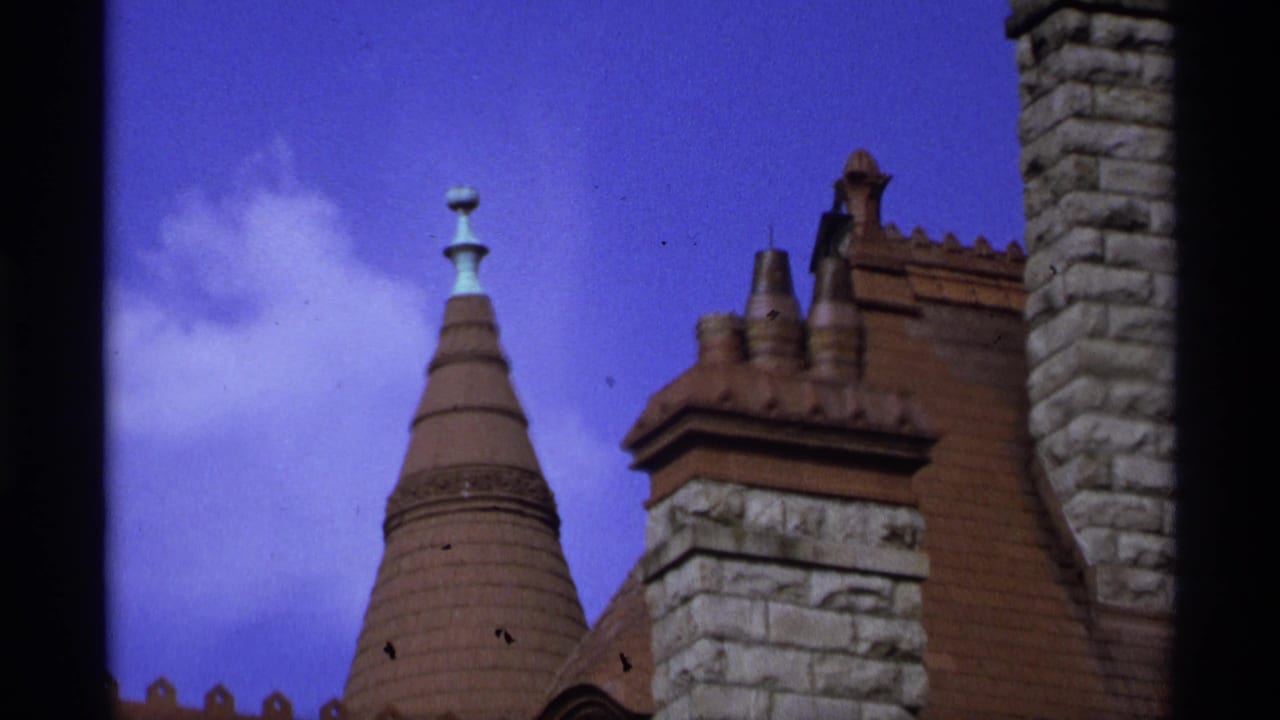Conical tiled roof, stone chimneys, and blue-purple sky.