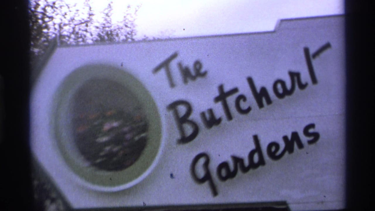 White The Butchart Gardens sign with black cursive lettering and circular flower inset.